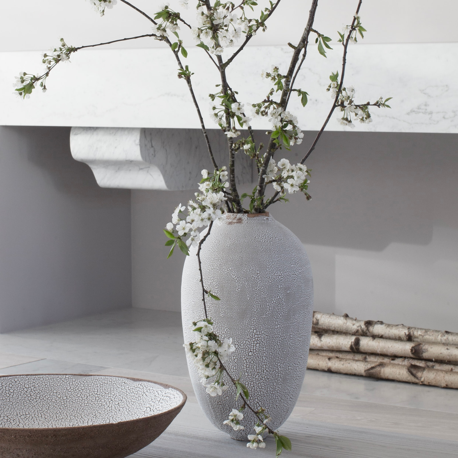 Kennedy Residence by Guillaume Alan — living room, large vase of blossoming branches and low bench, residence in Paris