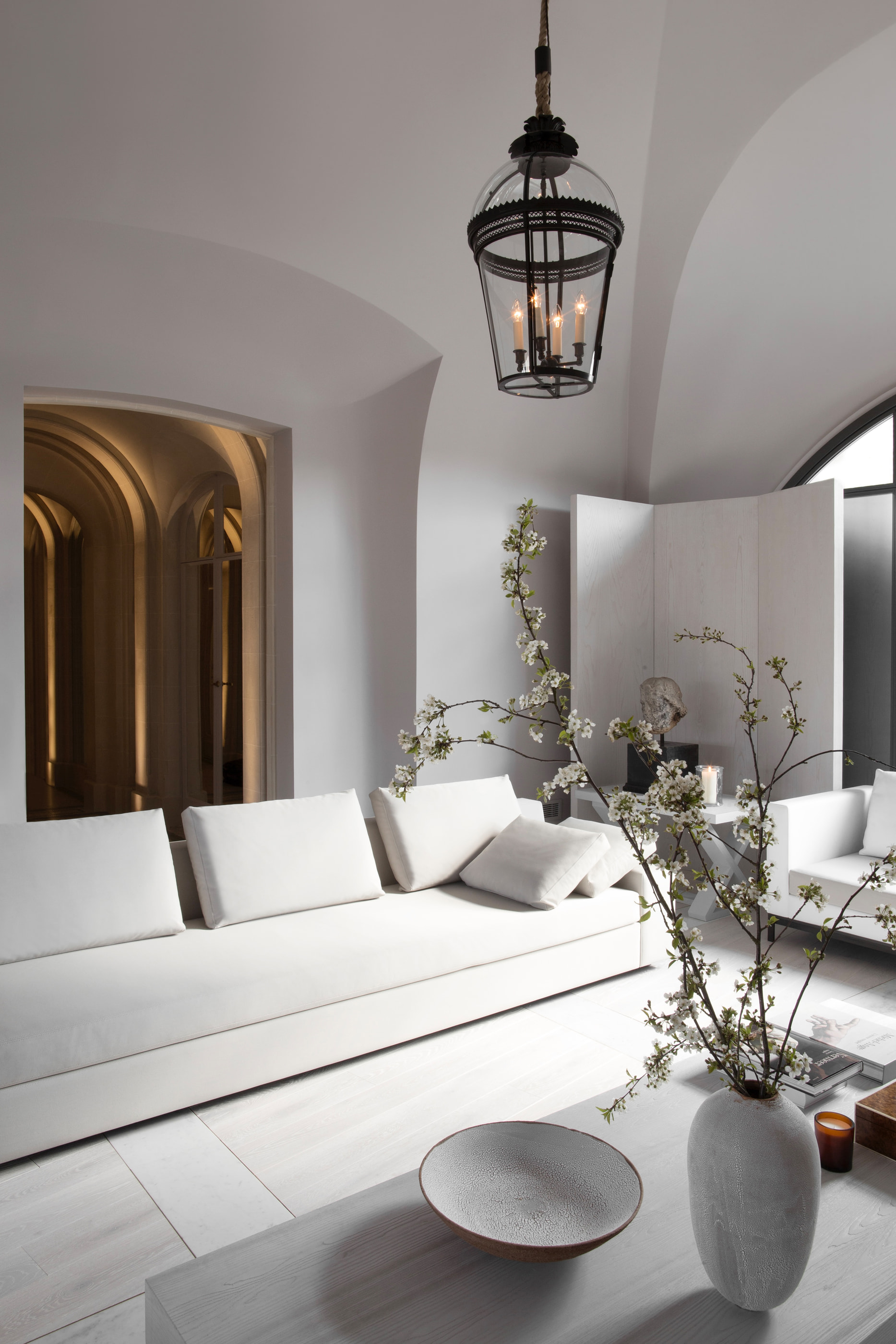 Kennedy Residence by Guillaume Alan — living room beneath a vault, white bench and branches in a vase, residence in Paris