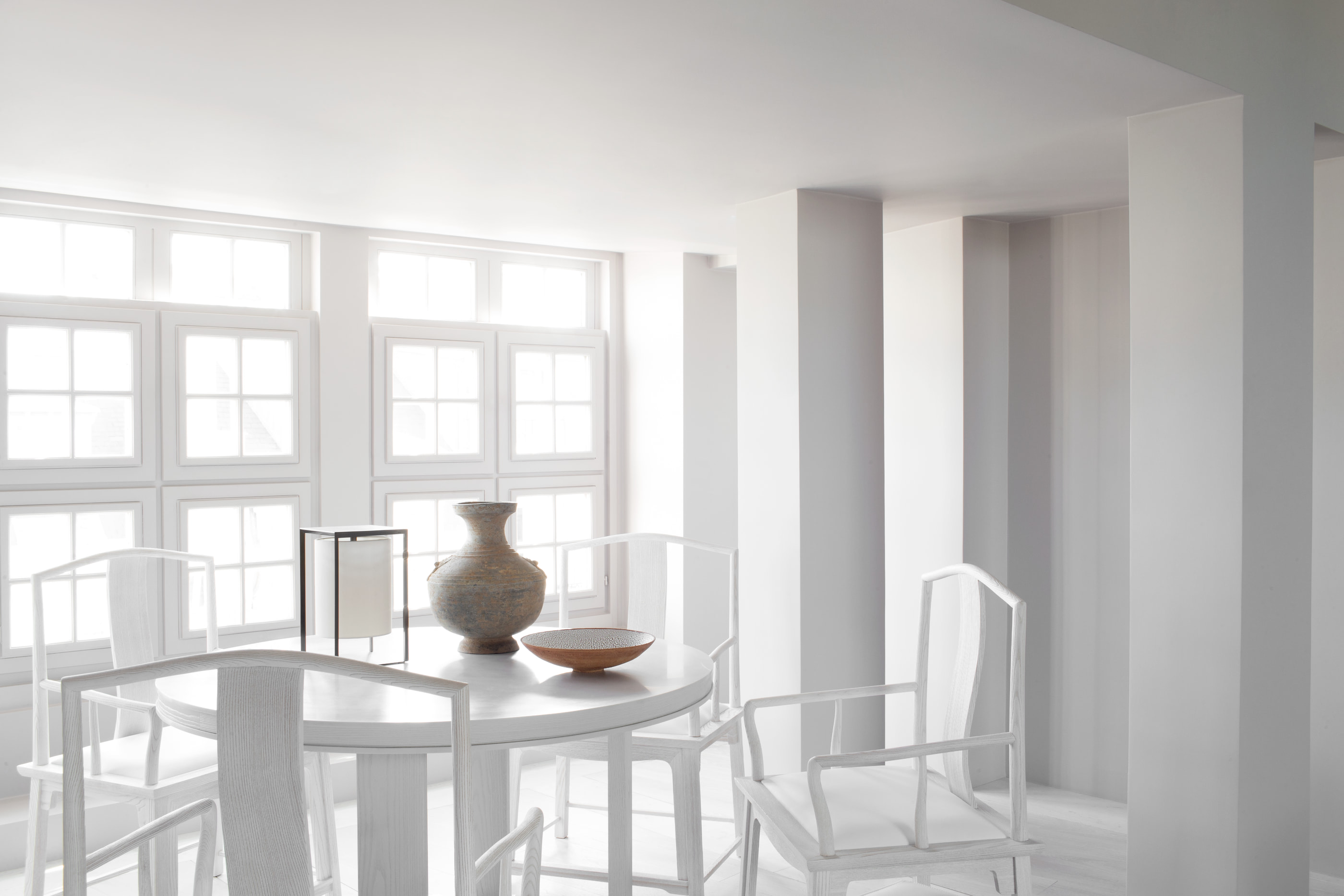 Kennedy Residence by Guillaume Alan — living and dining room in white, table and chairs in front of the multi-pane windows, residence in Paris