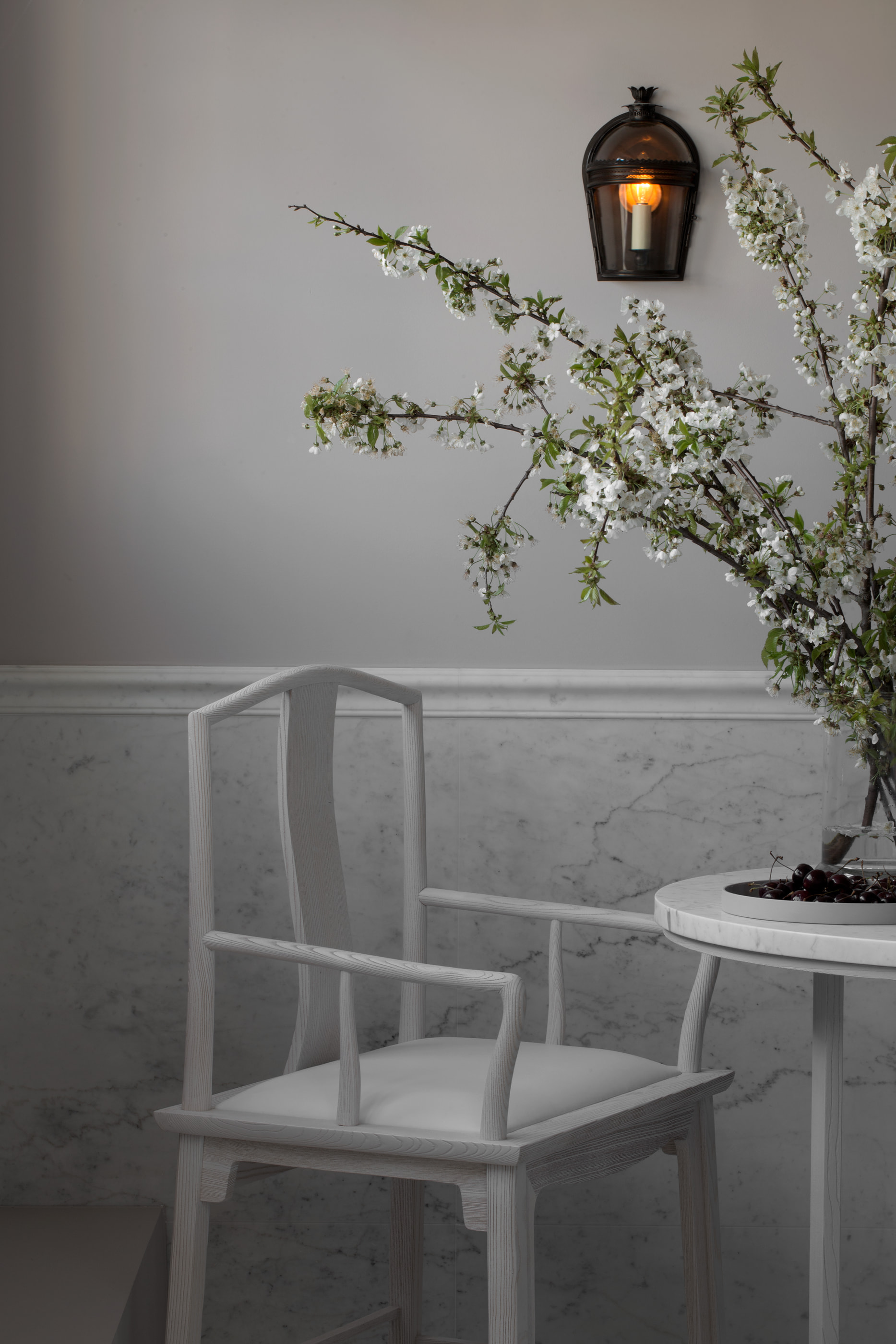 Kennedy Residence by Guillaume Alan — white chair and round table, blossoming branches and candle sconce, residence in Paris