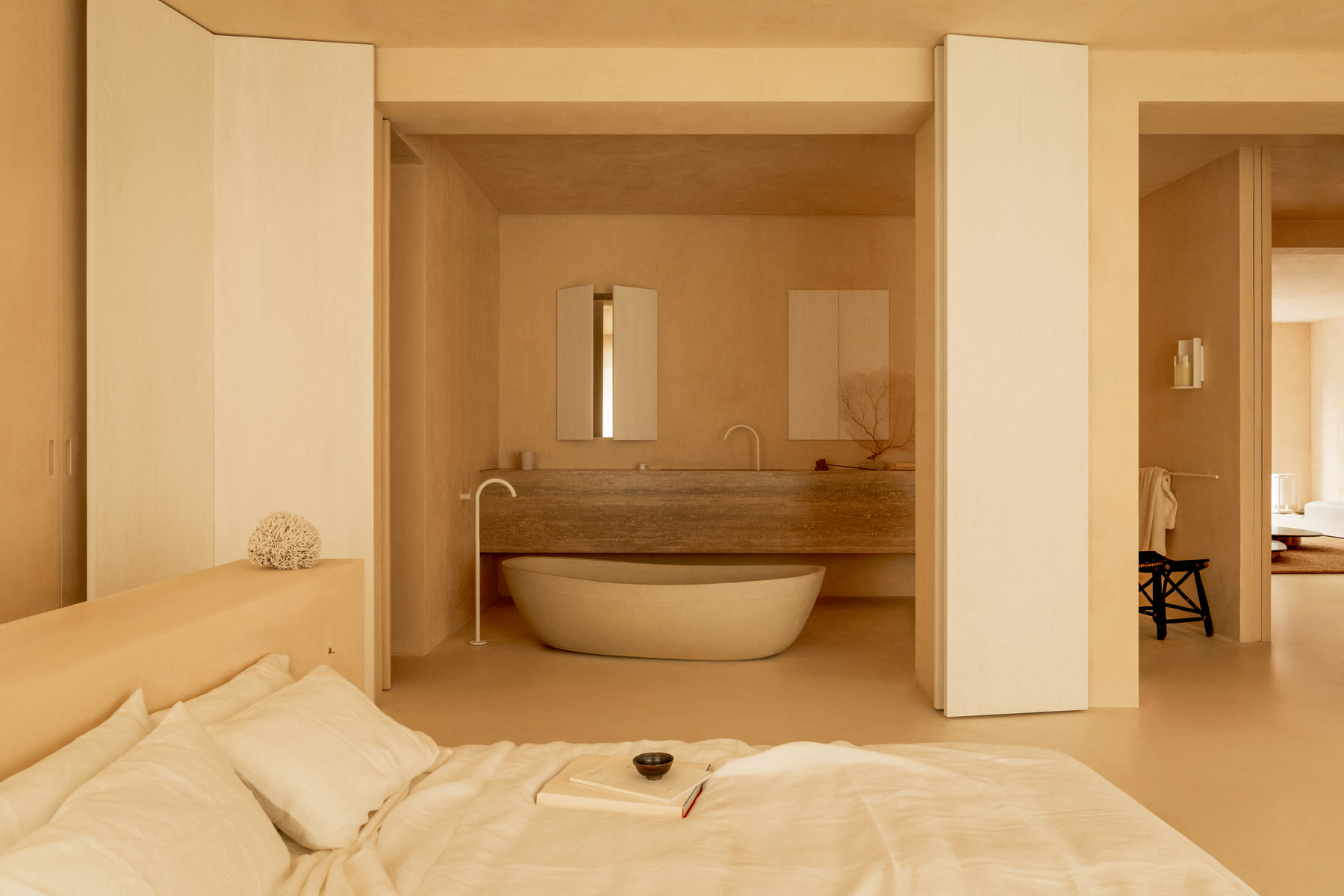 L’Imparfait by Guillaume Alan — bedroom opening onto the bathroom and its stone bath, apartment in Paris
