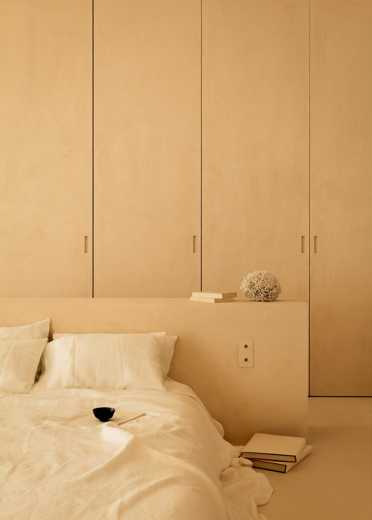 L’Imparfait by Guillaume Alan — bed against a wall of plaster wardrobes, apartment in Paris