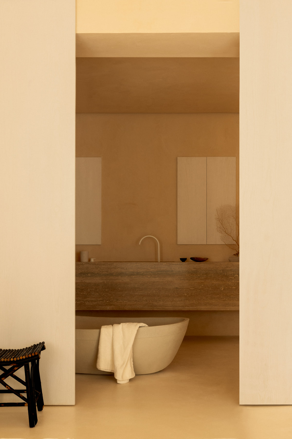 L’Imparfait by Guillaume Alan — doorway onto the bathroom, stone bath and wooden stool, apartment in Paris