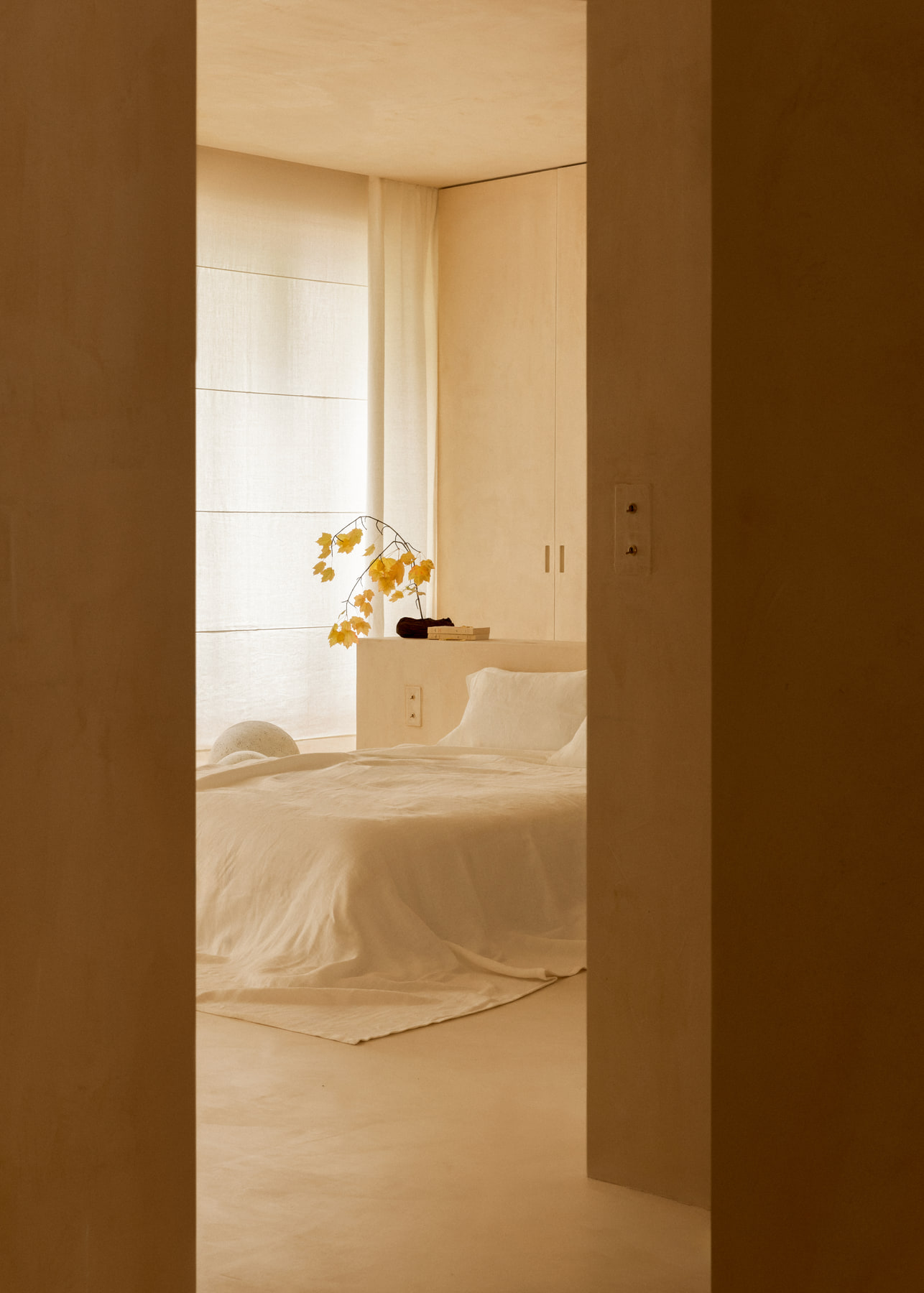 L’Imparfait by Guillaume Alan — bedroom glimpsed through a tall doorway, apartment in Paris