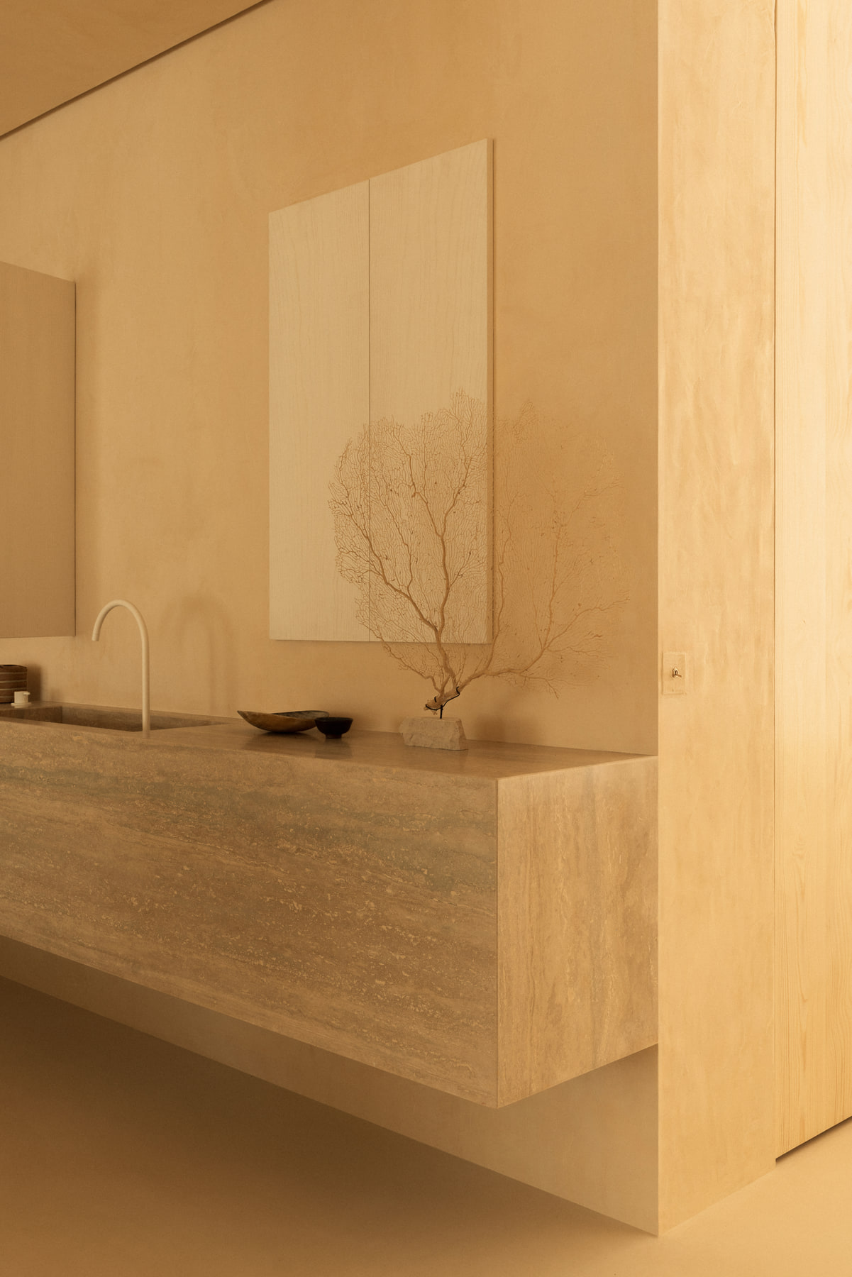 L’Imparfait by Guillaume Alan — travertine vanity with a coral branch, apartment in Paris