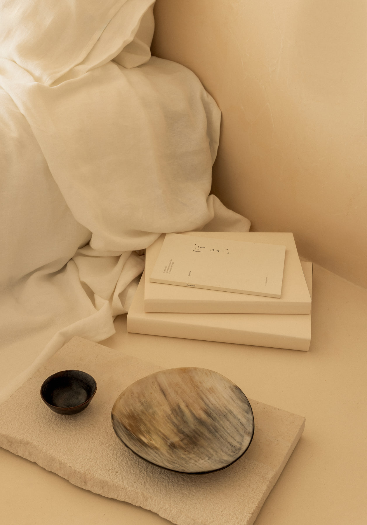 L’Imparfait by Guillaume Alan — books and bowls on a linen bed, apartment in Paris
