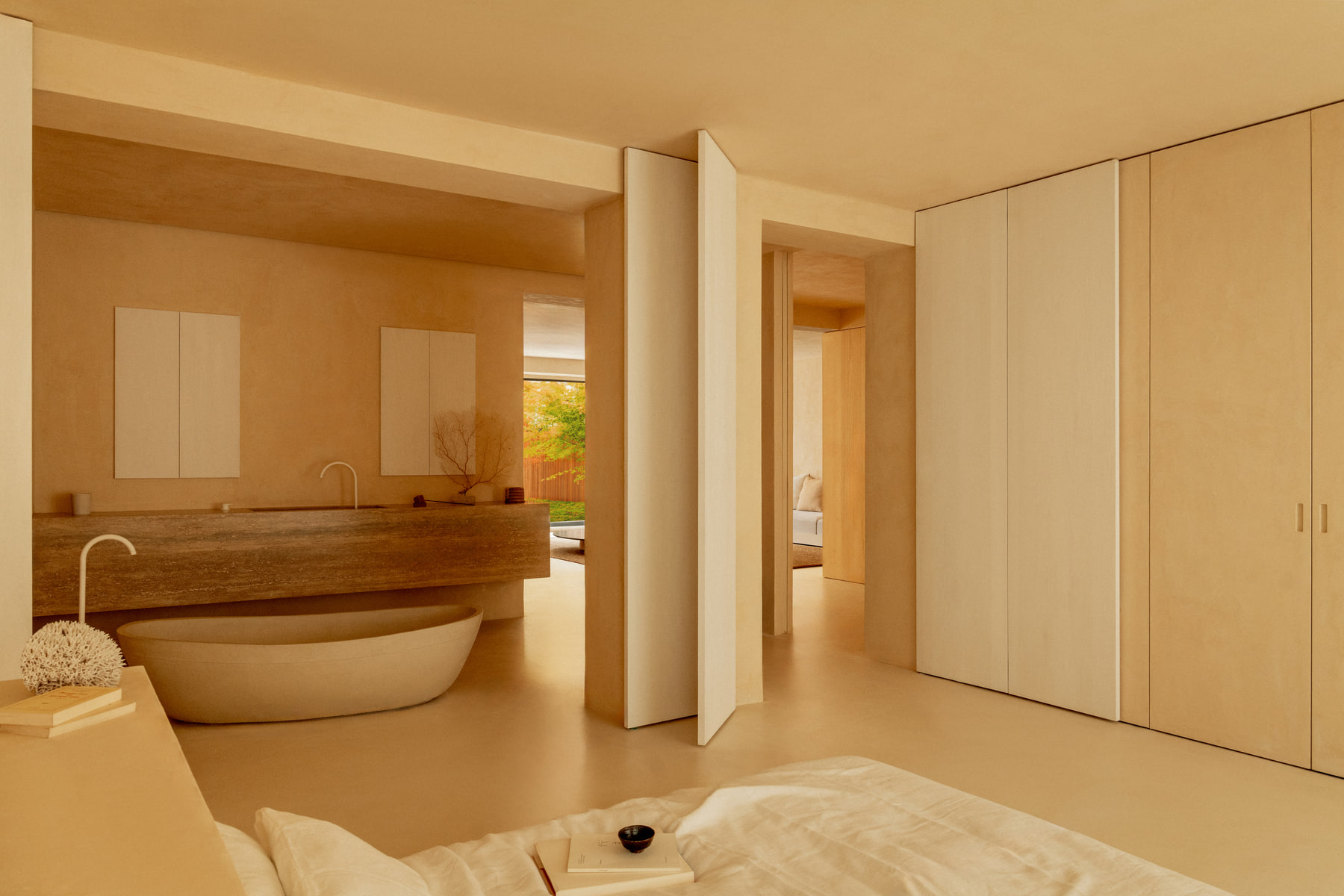 L’Imparfait by Guillaume Alan — bedroom opening onto the bathroom, travertine basin and stone bath, apartment in Paris