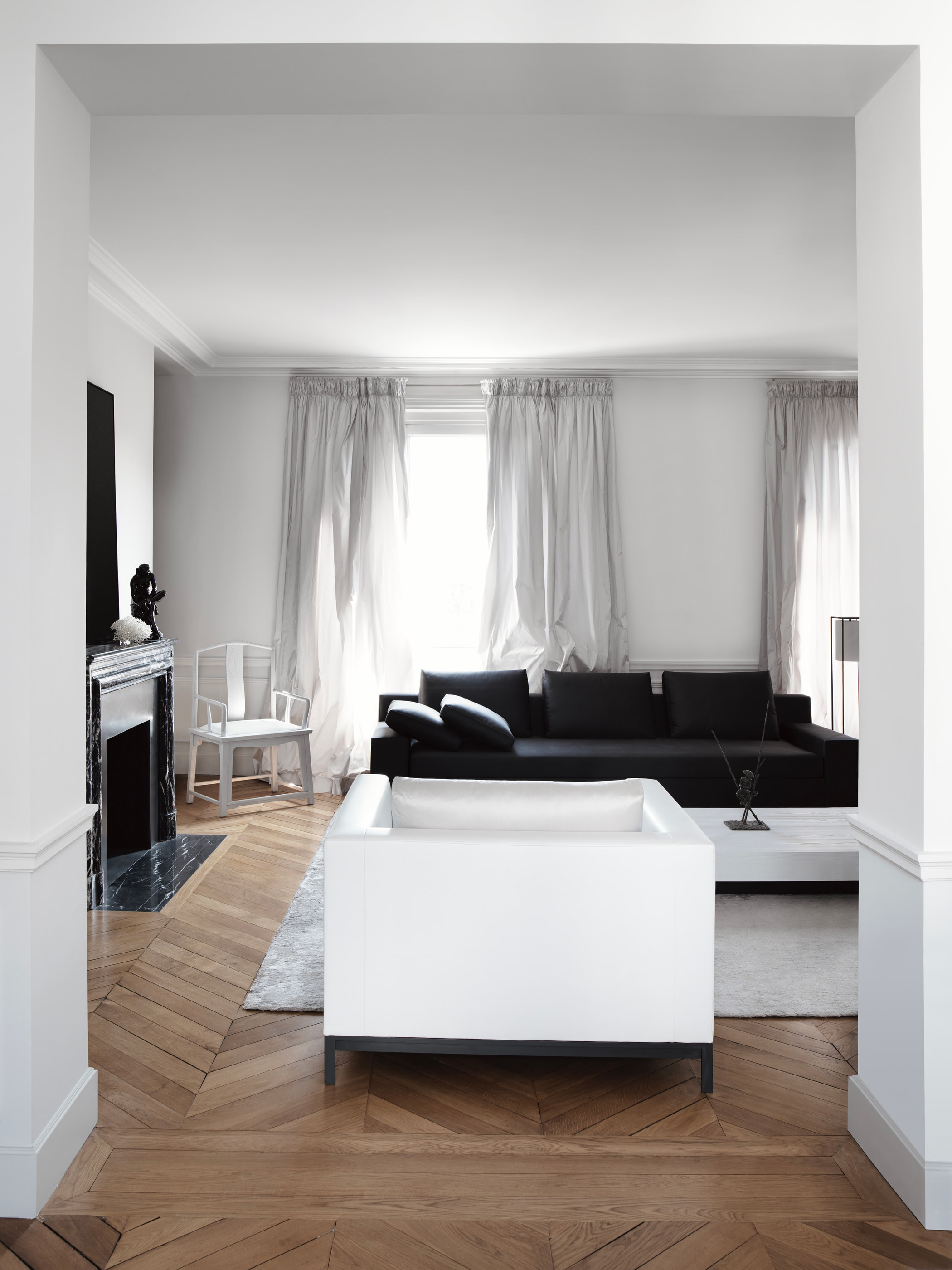 VH Penthouse by Guillaume Alan — living room, black sofa and white armchair in front of the fireplace, apartment in Paris